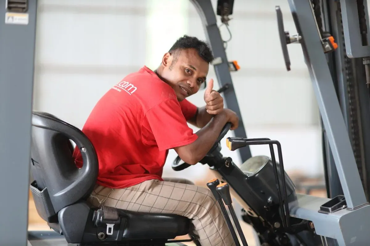 Worker driving forklift giving thumbs up