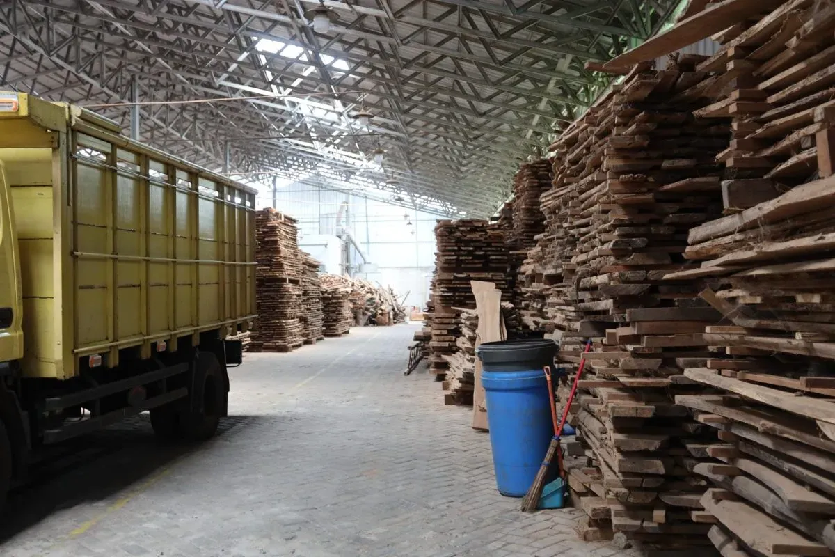 Warehouse with stacked wooden planks and yellow truck