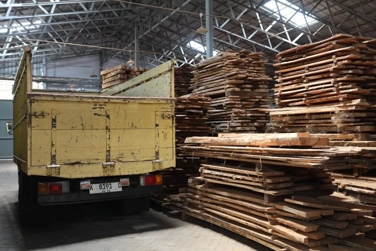 Yellow truck near stacked wooden planks in warehouse