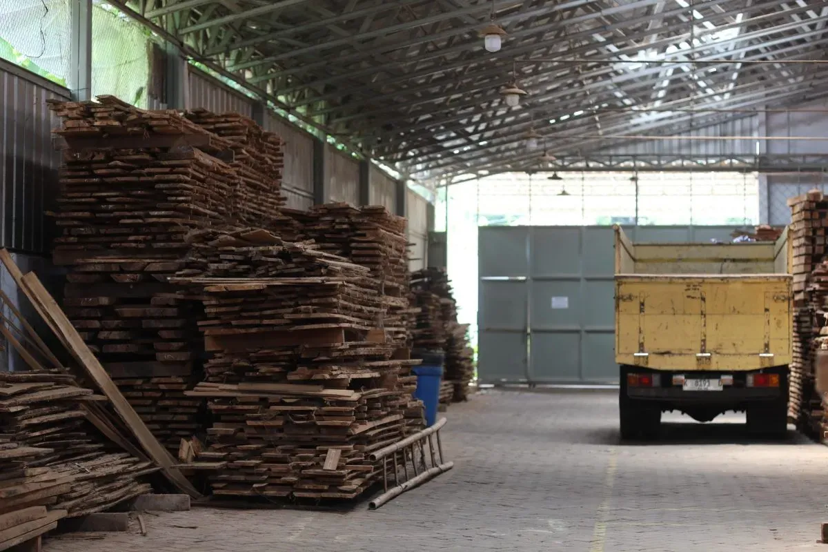 Stacked wooden planks inside warehouse with yellow truck