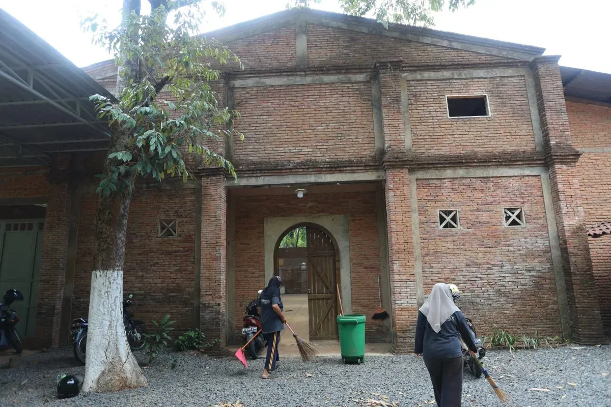 People sweeping outside brick building