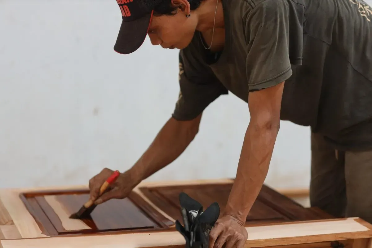 Person staining wooden cabinet panels