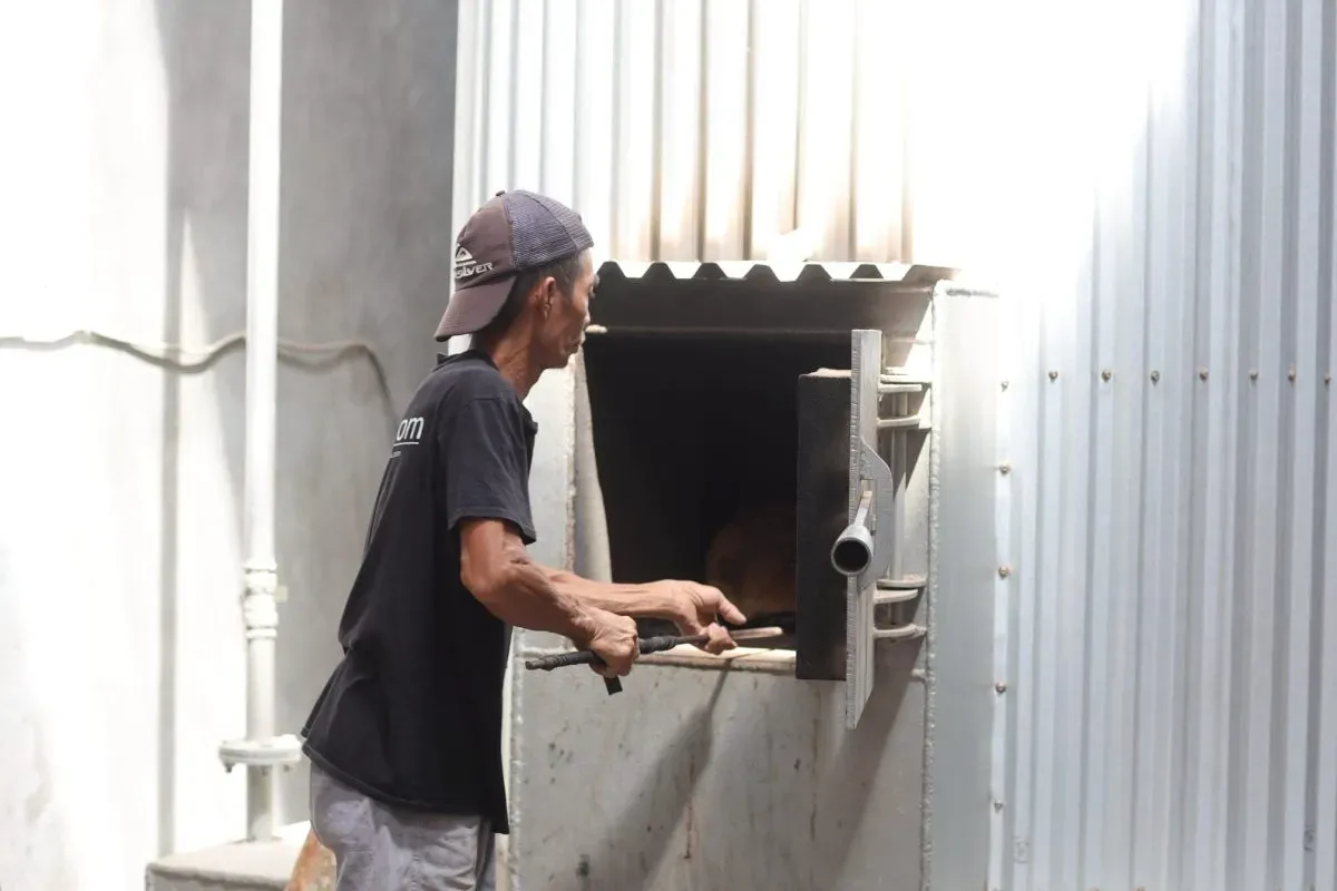 Worker operating industrial furnace outdoors
