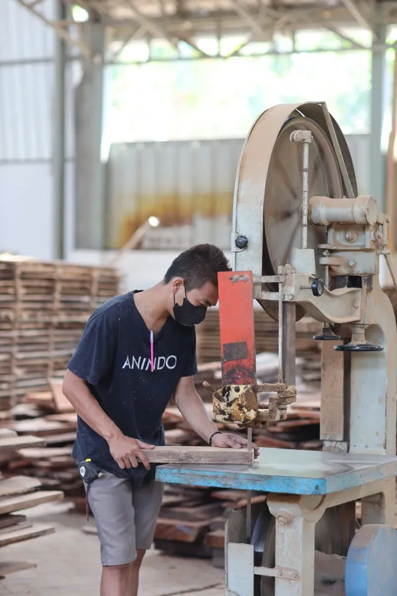 Worker cutting wood with industrial bandsaw