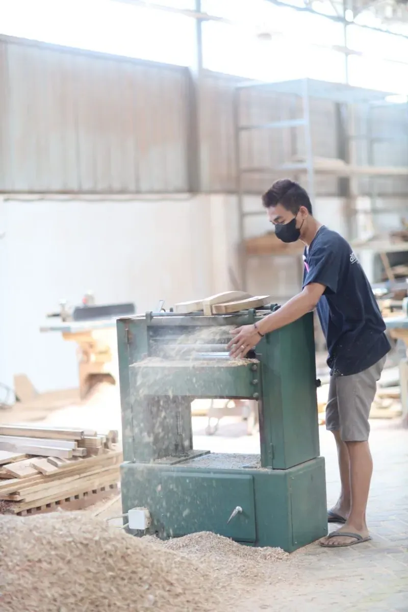 Worker using wood planer in carpentry workshop