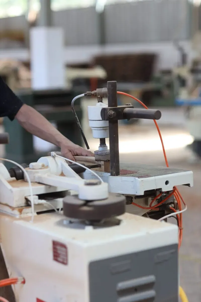 Worker operating industrial drilling machine in workshop