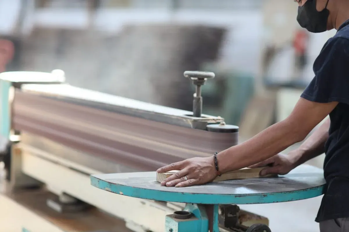 Worker sanding wood on industrial machine
