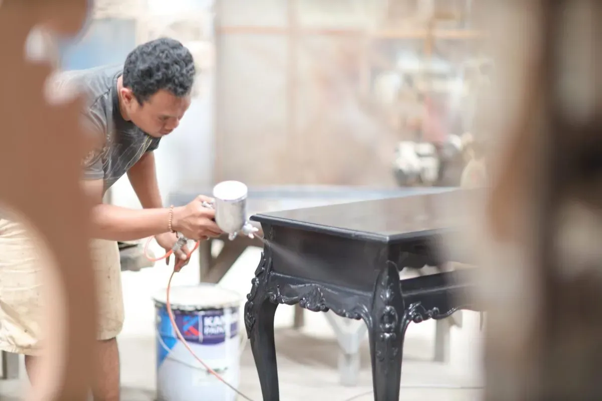 Man spray painting a wooden table black