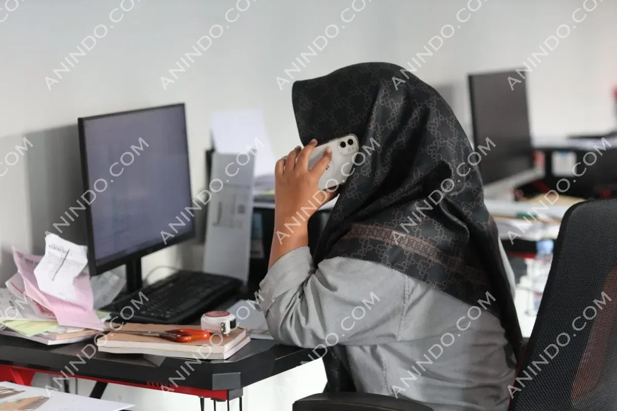Person on phone working at computer desk
