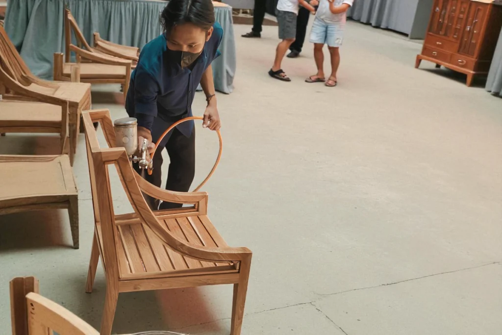 Person spray painting a wooden chair indoors