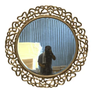 Decorative round mirror with intricate golden frame.